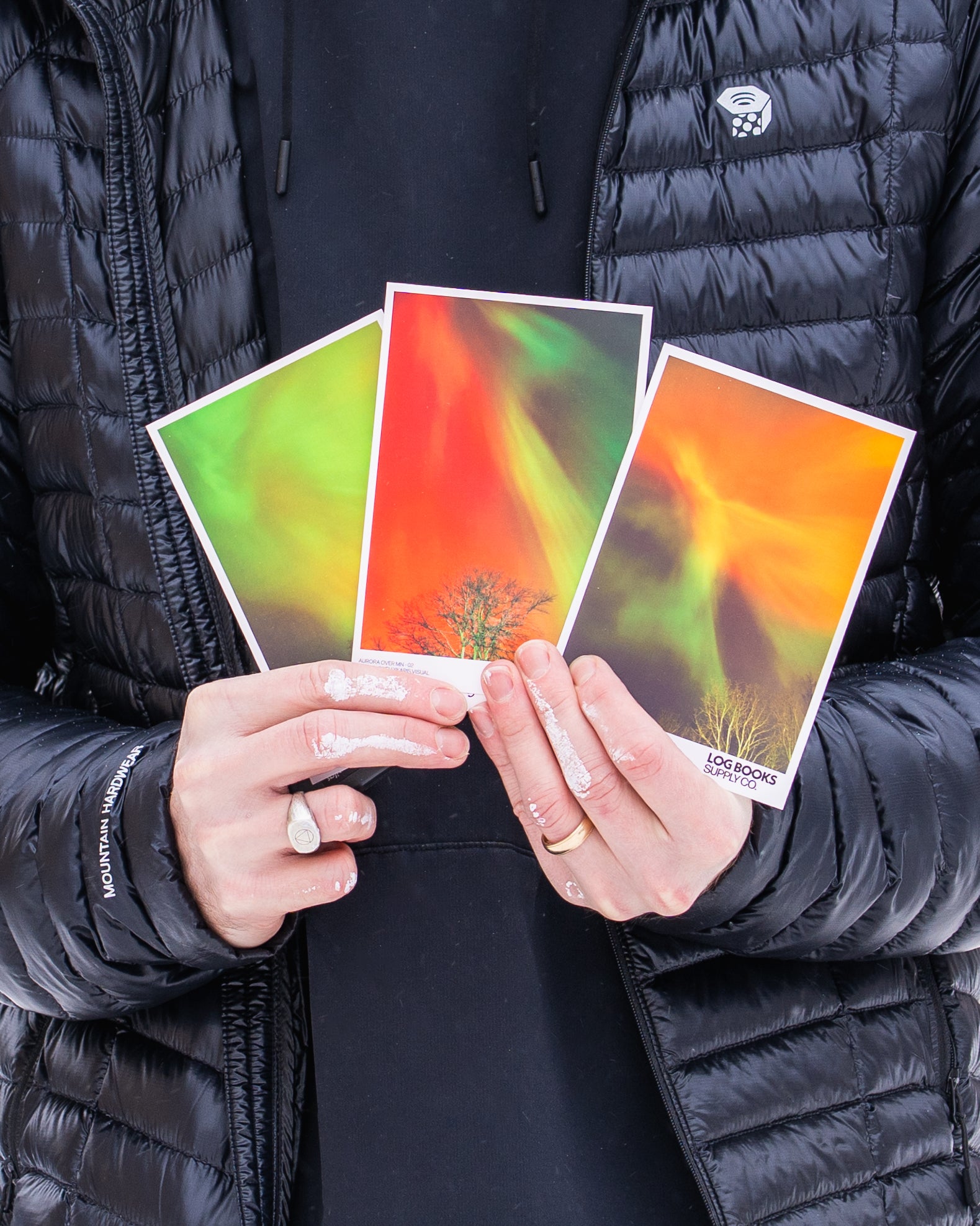 Person holding three colorful cards with a black jacket